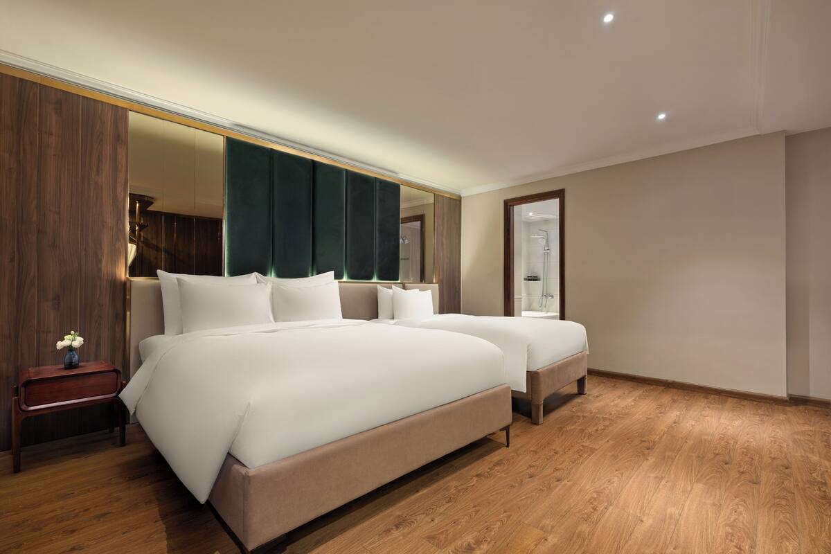 A modern hotel room with a large bed, a bedside table, and a mirror.