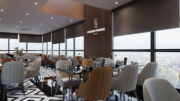 A modern dining area with geometric patterned flooring, contemporary furniture, and large windows offering a city view.