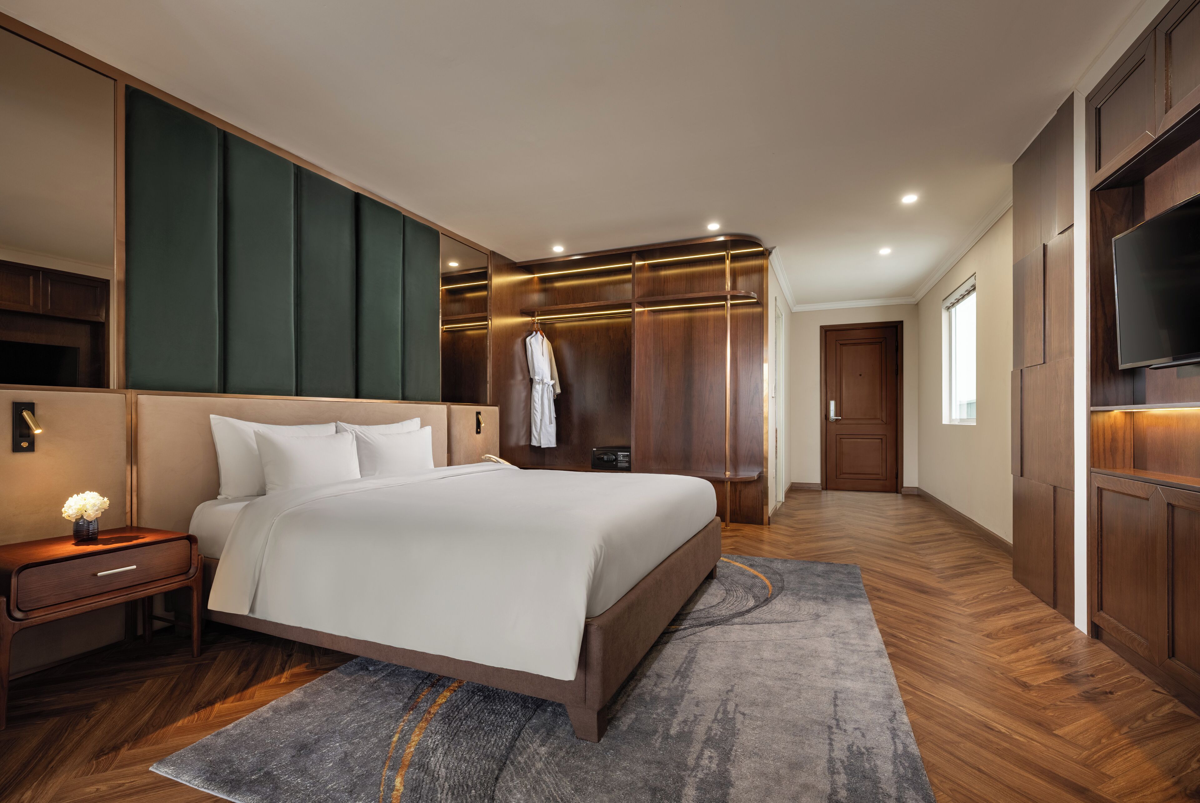 A modern bedroom with a large bed, wooden wardrobe, and a flat-screen TV.