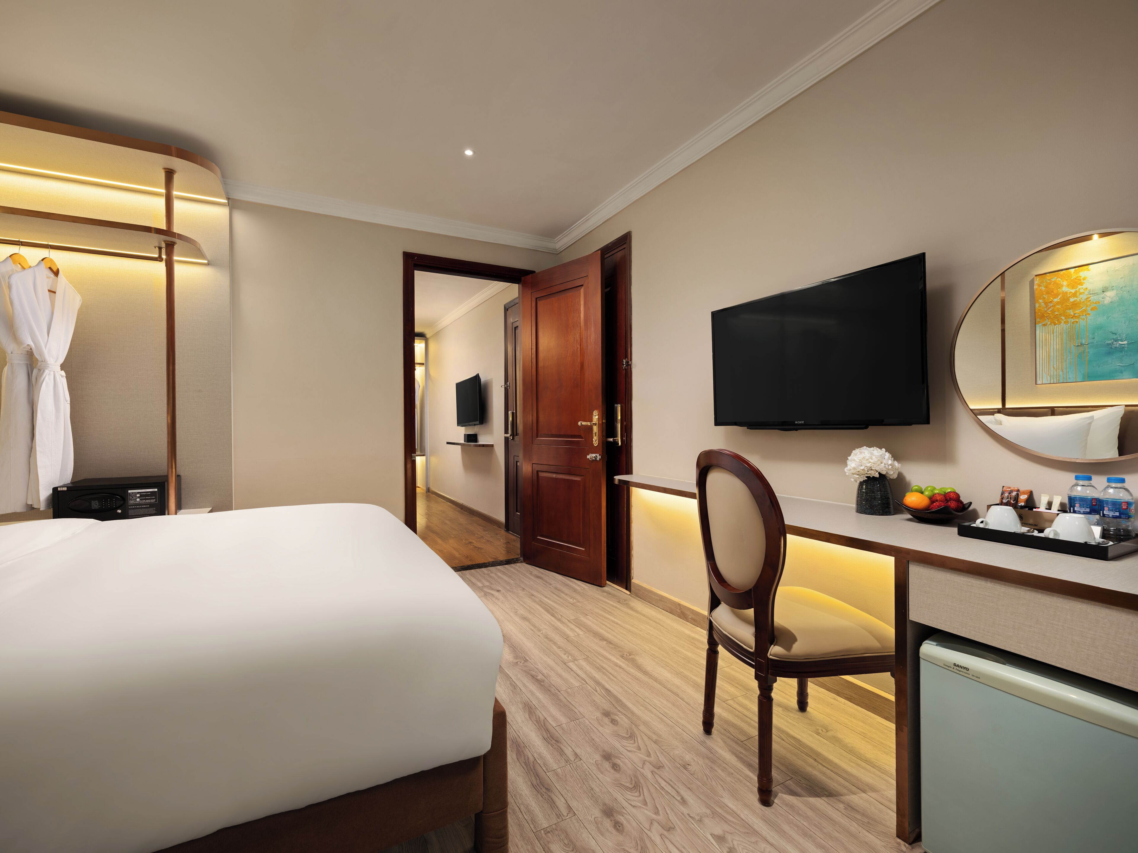 A hotel room with a bed, a desk, a chair, a television, and a small refrigerator.
