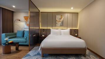 A modern hotel room with a large bed, a sofa, a coffee table, and a decorative wall piece.