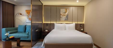 A modern hotel room with a large bed, a sofa, a coffee table, and a decorative wall piece.