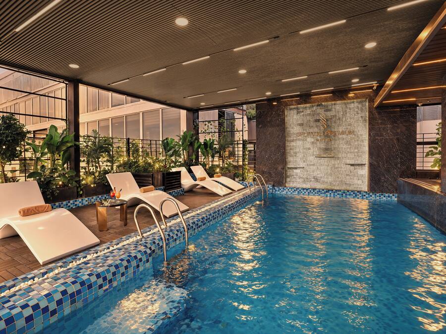 Una piscina interior moderna con sillas de descanso y un borde de azulejos.