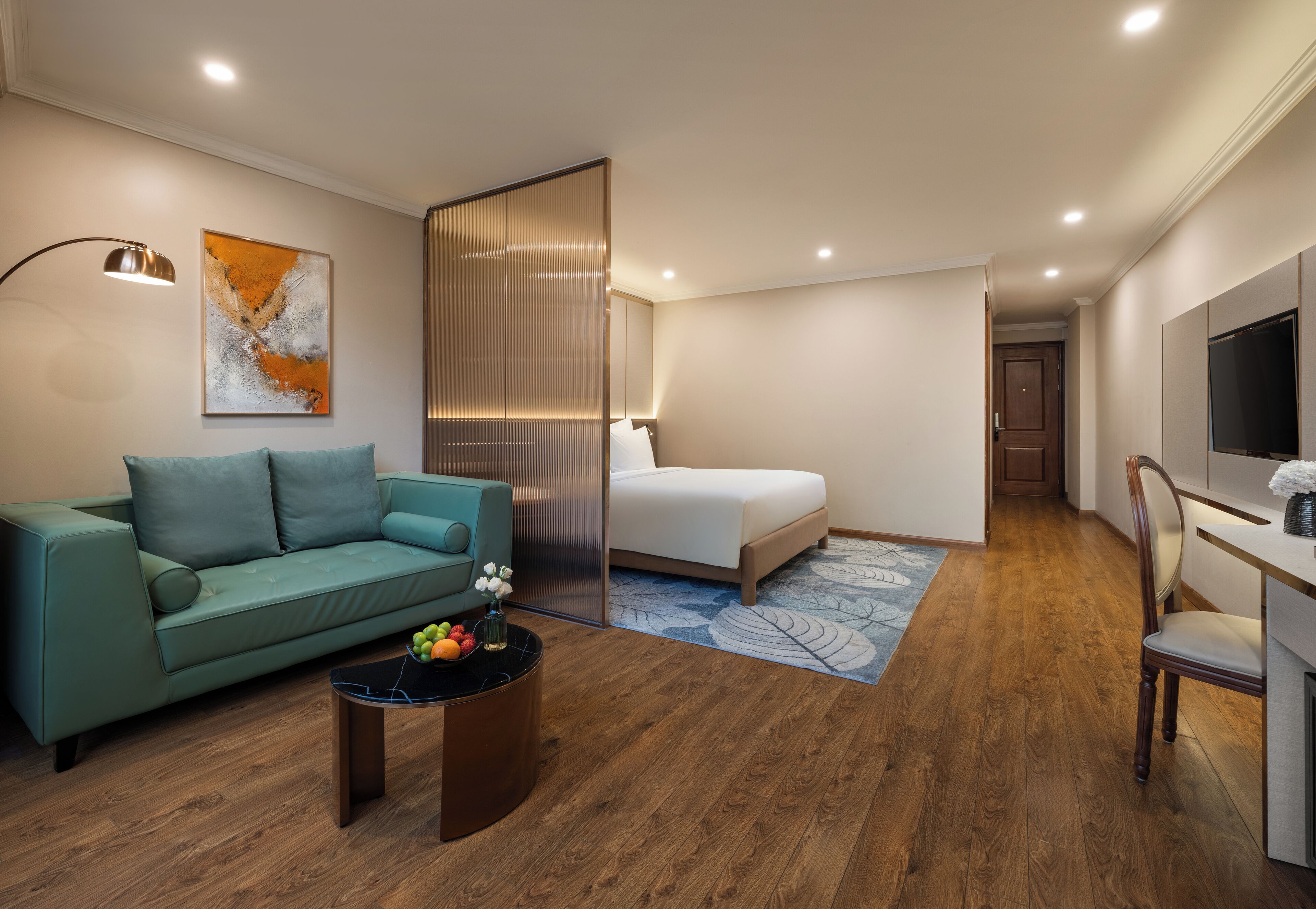 Una habitación de hotel moderna con sofá, cama, escritorio y televisor.