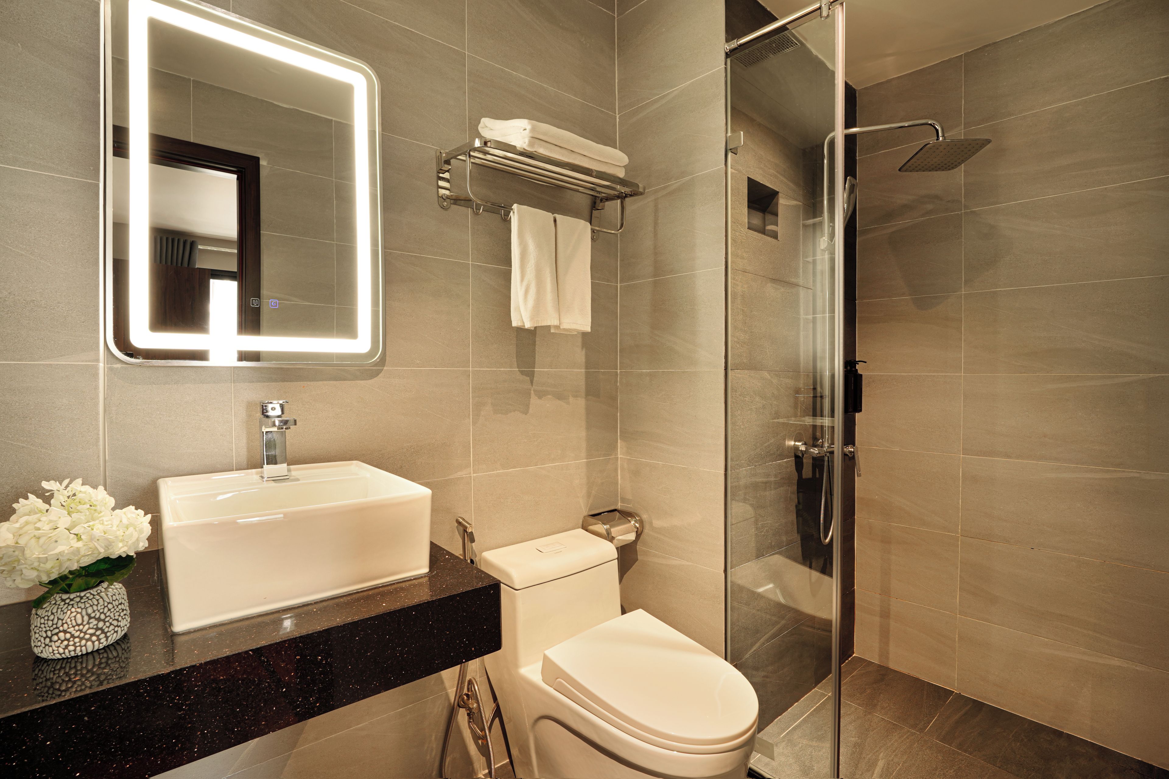 Een moderne badkamer met een wastafel, toilet en douchecabine met glazen wanden.