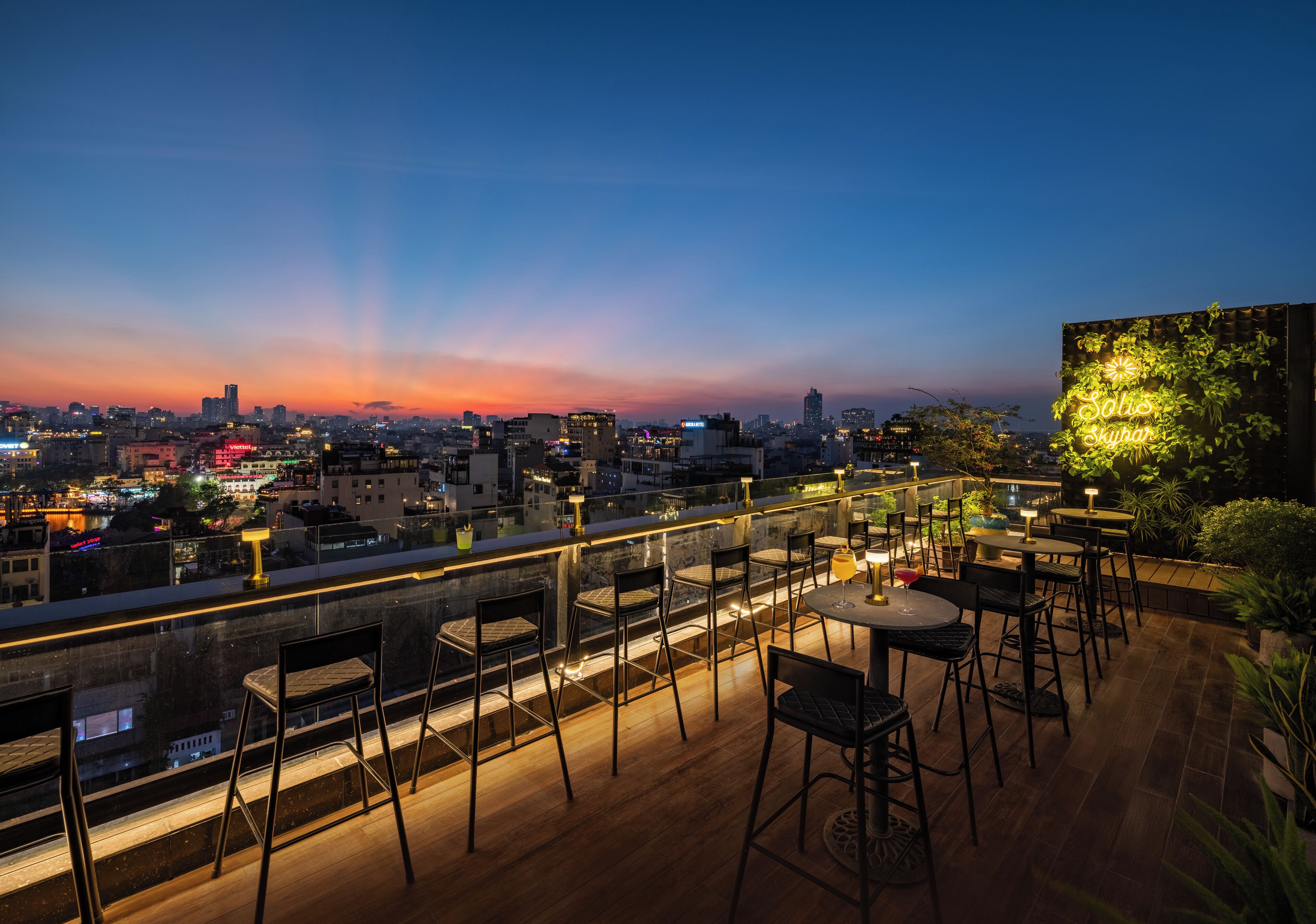 A rooftop terrace with outdoor seating and a city view at dusk.