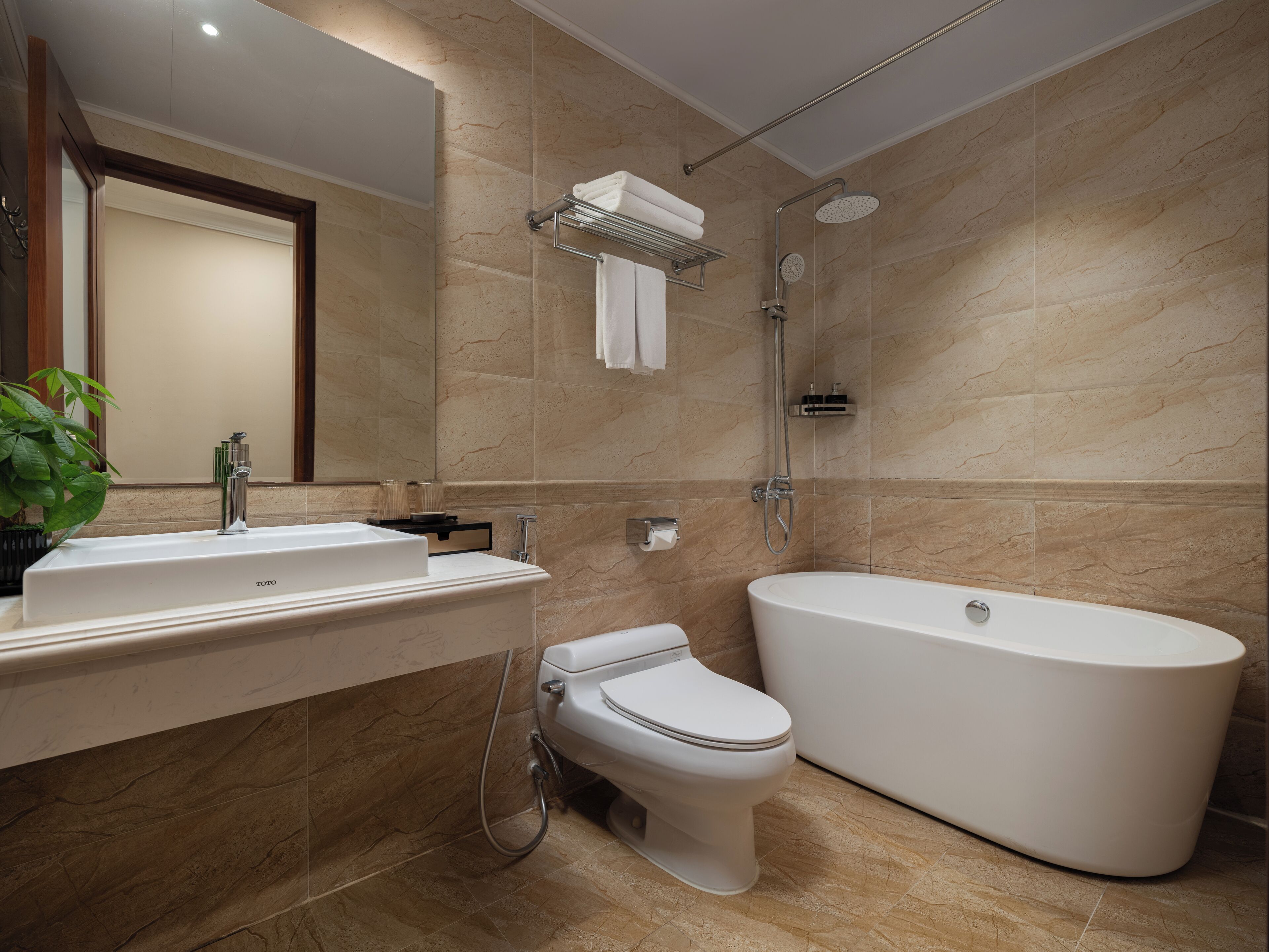 A modern bathroom with a freestanding bathtub, a toilet, and a sink with a mirror.
