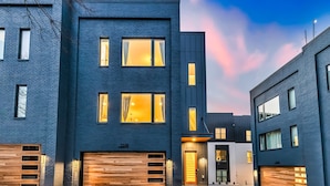 A modern two-story building with a garage door and a well-lit entrance. - Nashville getaway: 2 homes, 2 rooftop hot tubs, sleeps 24 near Geodis Park (Nashville)