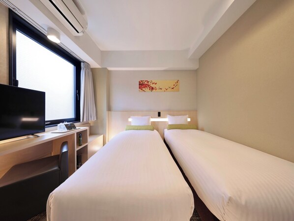 Una habitación de hotel con dos camas, un escritorio con televisor y un ventanal con cortinas.
