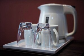 Una bandeja blanca con dos vasos transparentes y una tetera blanca sobre una mesa.