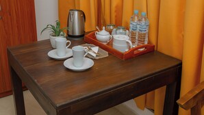 A wooden table with a tray holding a teapot, cups, a small plant, and water bottles. - The Regency villa by Escape Essence  (Unawatuna)