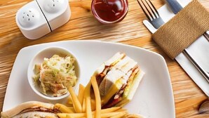 A plate with sandwiches and fries, a small bowl of coleslaw, and condiments on a wooden table. - The Regency villa by Escape Essence  (Unawatuna)