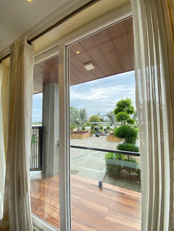 A room with a sliding glass door leading to an outdoor patio area. - Evaara By The Ganges (Haridwar)
