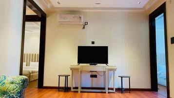Una sala de estar moderna con un televisor de pantalla plana, dos mesitas auxiliares, un sofá y un aire acondicionado instalado en el techo.