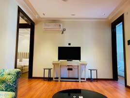 Una sala de estar moderna con un televisor de pantalla plana, dos mesitas auxiliares, un sofá y un aire acondicionado instalado en el techo.