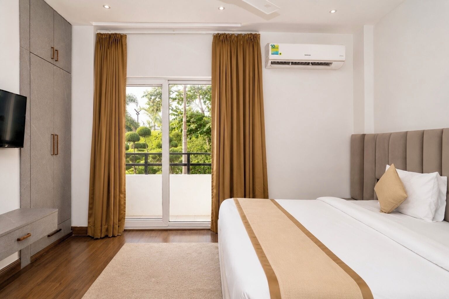 Una habitación de hotel con cama, televisor, armario y aire acondicionado.