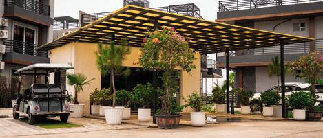 A modern building with a covered parking area, potted plants, and a golf cart.