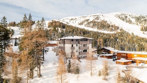 Un hôtel moderne à plusieurs étages, avec une piste de ski en arrière-plan.