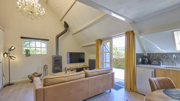 A spacious living room with a large sofa, a television, a fireplace, and a dining area with a table and chairs.
