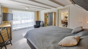 A bedroom with a bed, a desk with a television, a chair, and a wardrobe.