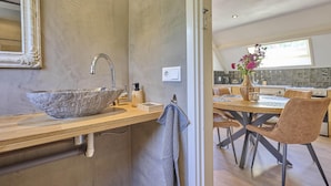 A modern bathroom with a large vessel sink, a mirror, and a towel hanging on the wall.