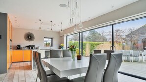 A modern kitchen with a dining area, large windows, and a view of the outdoors. - Whitstable | 4 bd | Pool | Games Room | Cinema (Kent)