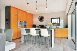 Cozinha moderna com ilha central, banquetes e um painel decorativo.
