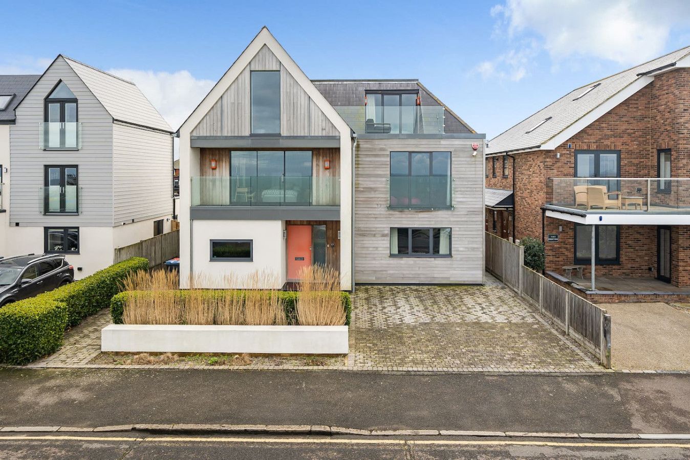 A modern two-story house with a flat roof, large windows, and a visible balcony.