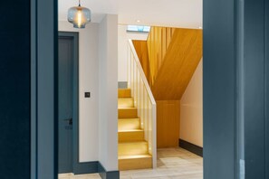 Interior moderno com escada, porta e luminária pendente.