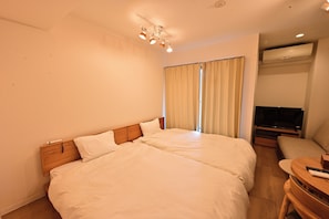 A hotel room with a large bed, a TV, and a small seating area. - 10 minutes from downtown Osaka, washer/dryer in the bedroom, 20 minutes to USJ, 30 minutes to Namba (大阪市)