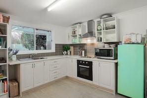 Eine moderne Küche mit weißen Schränken, einem Einbauofen, einer Mikrowelle und einem grünen Kühlschrank.