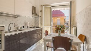 A modern kitchen with a dining area, featuring a large window, a dining table with chairs, and a view of the outside. - Quadri D'oro (Loano)