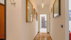A hallway with marble flooring, framed mirrors, and a wooden panel on the left. - Quadri D'oro (Loano)