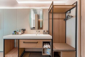 A modern bathroom with a large mirror, a sink with a towel rack, and a wooden vanity with storage drawers. - Homeinn Plus - Zhangjiajie Tianmenshan (Zhangjiajie)