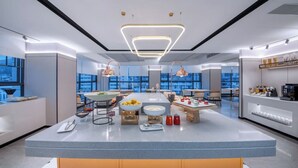 Una cocina moderna con una isla central, iluminación colgante y vistas a la ciudad.