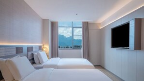 A hotel room with two beds, a large window with a view of mountains, a flat-screen TV mounted on the wall, and a light-colored tiled floor. - Homeinn Plus - Zhangjiajie Tianmenshan (Zhangjiajie)