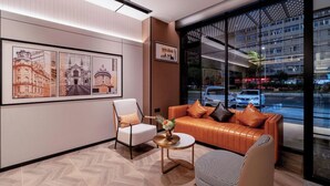 A modern hotel lobby with a large window offering a view of the cityscape, a seating area with a sofa and chairs, and framed artwork on the wall. - Homeinn Plus - Zhangjiajie Tianmenshan (Zhangjiajie)