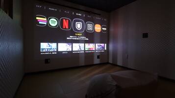 A room with a wall-mounted display featuring various media icons and a selection of video thumbnails.
