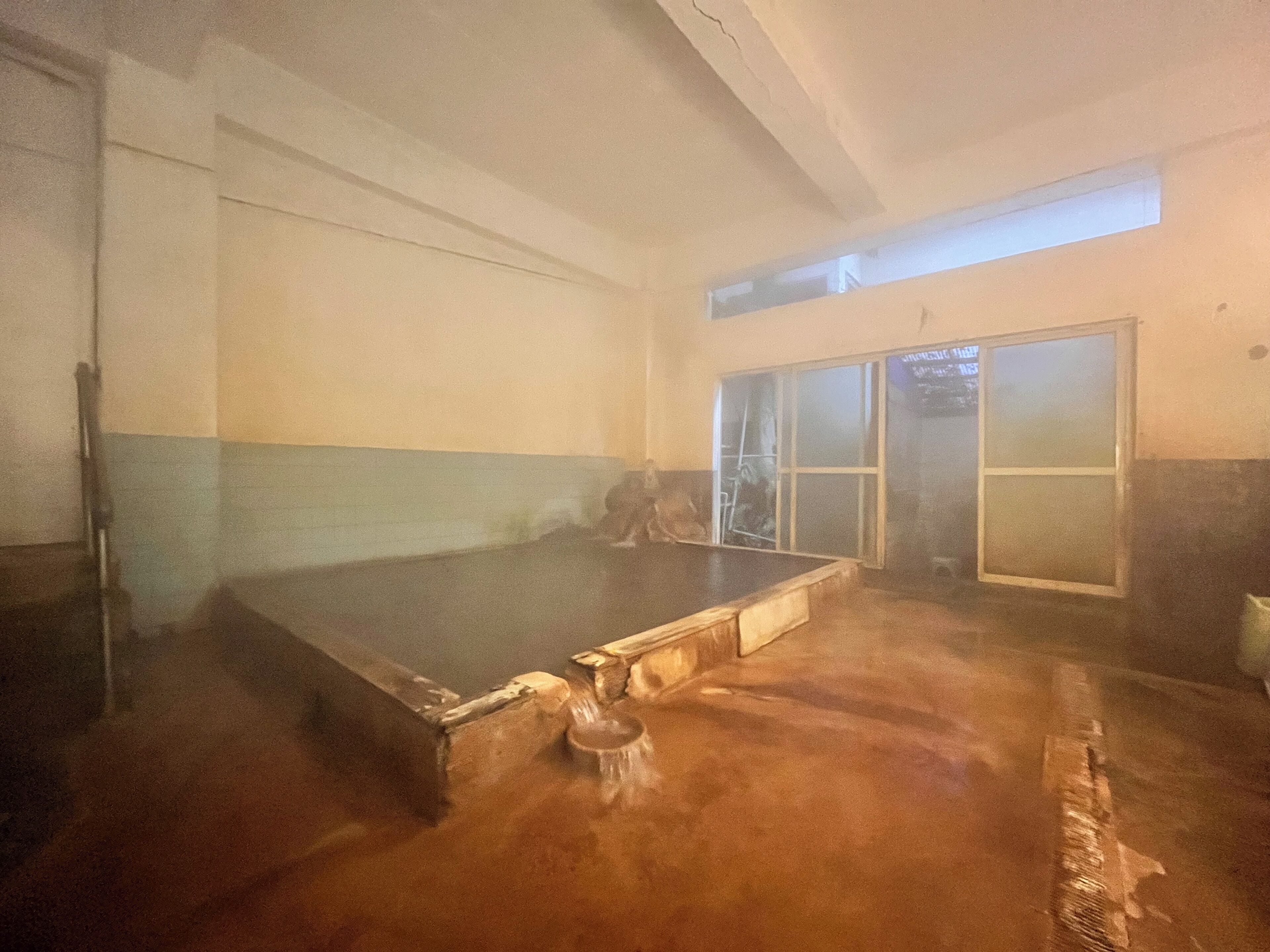 Un'ampia stanza con un grande tavolo da biliardo scuro, un piccolo sgabello e una porta scorrevole in vetro che dà su un'area esterna.