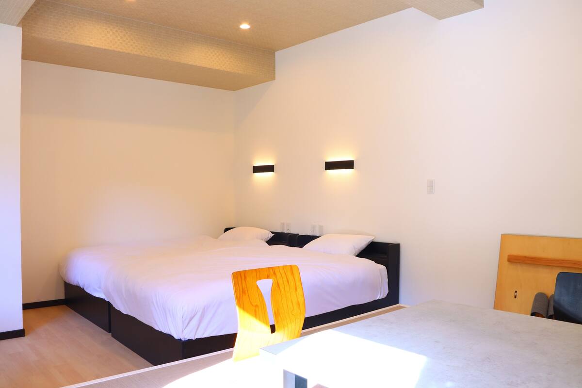 Une chambre moderne avec un grand lit, deux tables de chevet et une tête de lit en bois.