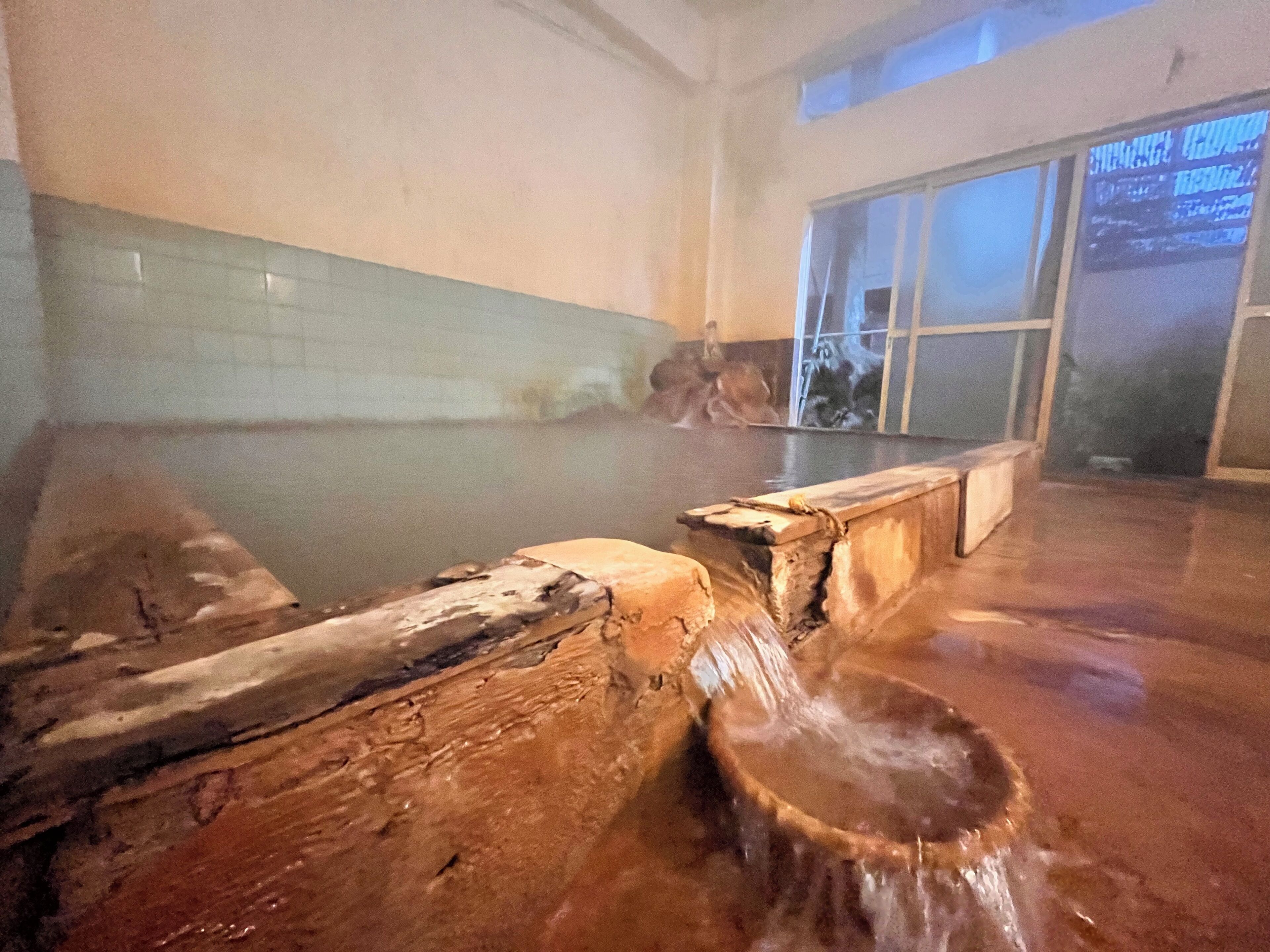 A hot spring area with a wooden bench and a stone basin.