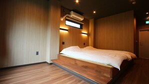 A bedroom with a bed, wooden flooring, an air conditioning unit, and a door. - Myoukenkan (Kirishima)
