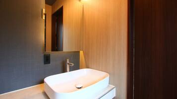 A modern bathroom with a white sink, a mirror, and a light fixture above the mirror.