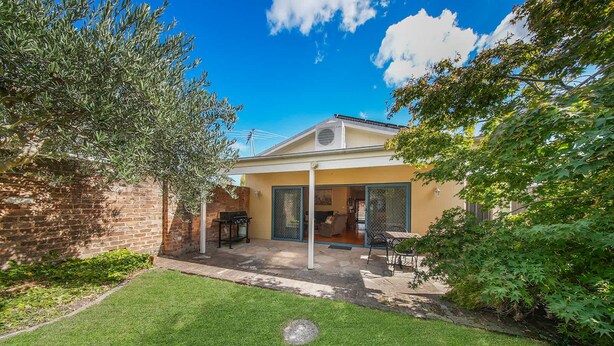 Uma casa com um pátio, churrasqueira e área de estar coberta ao ar livre.