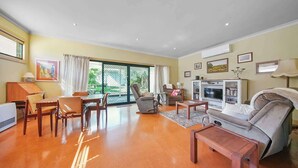 Uma sala de estar espaçosa com área de jantar, sofá, televisão e lareira.