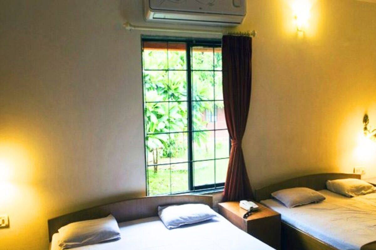 Una habitación de hotel con dos camas, una ventana con cortinas e iluminación en la pared.
