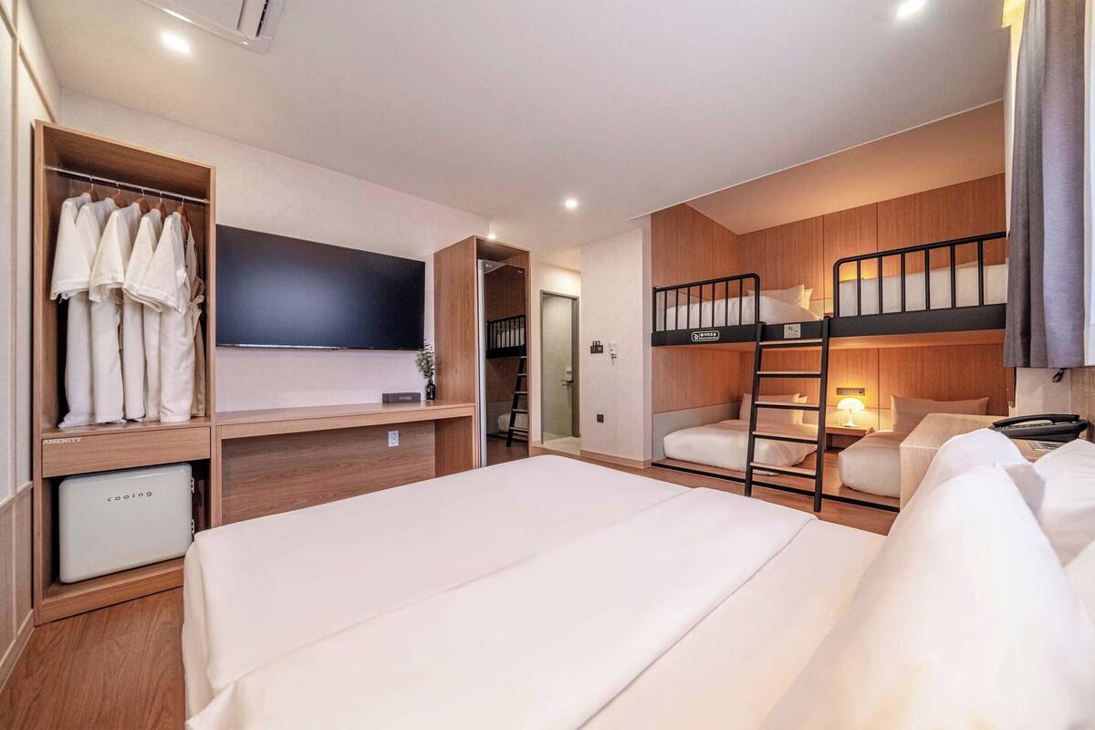 Habitación de hotel con literas, armario, escritorio y televisor.