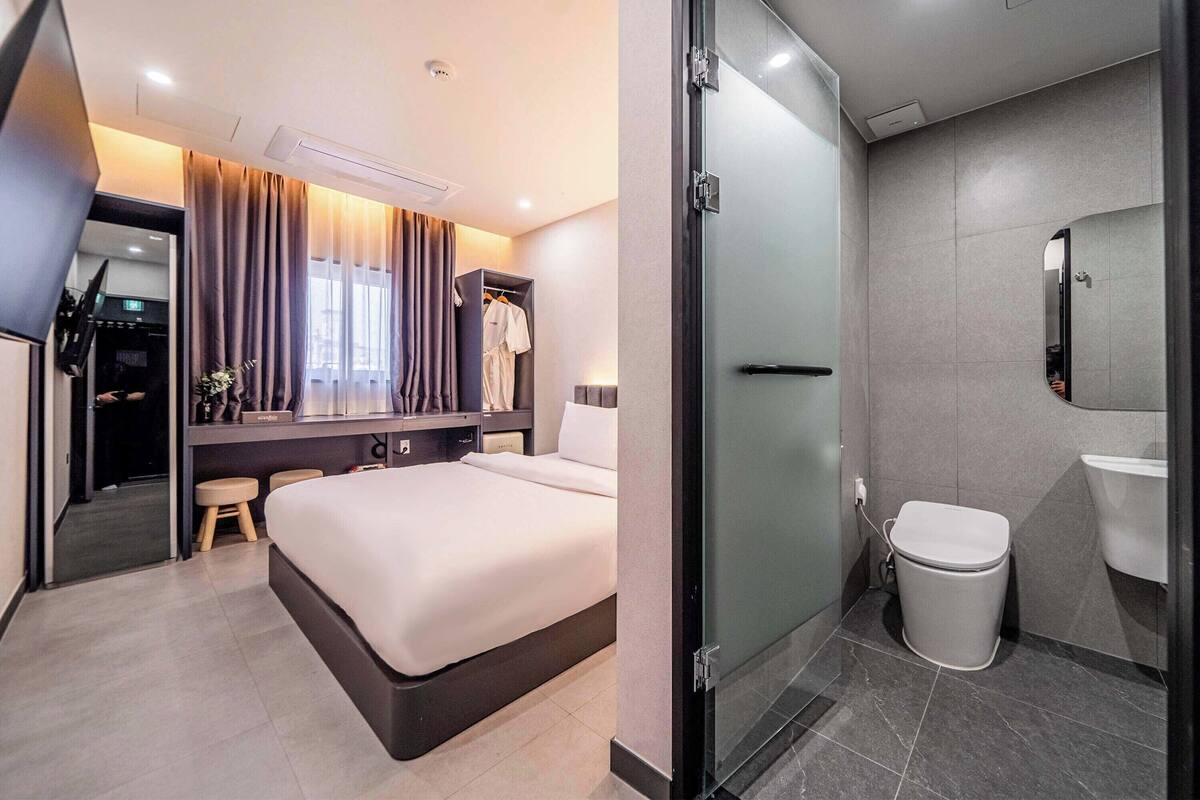 Una habitación de hotel con cama, mesita de noche y espejo.
