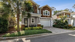 A two-story house with a garage, a front porch with a bench, and a well-maintained garden. - Seashell Cove | Pet-friendly, Bikes, & Short walk to Egan's Creek! (Fernandina Beach)