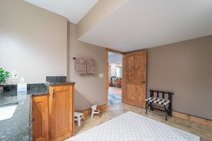 A bathroom with a wooden cabinet, two stools, a bench, and a towel rack. - Beautiful Cabin on 5 Acres • Pond • Decks • Close to Everything (Marble)